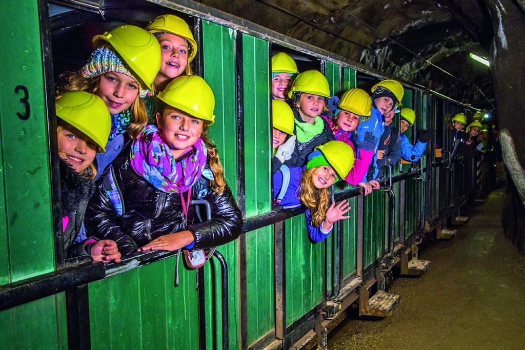 Kinder mit gelben Schutzhelmen fahren mit der „Katl“ durch das Schaubergwerk im Erzberg.