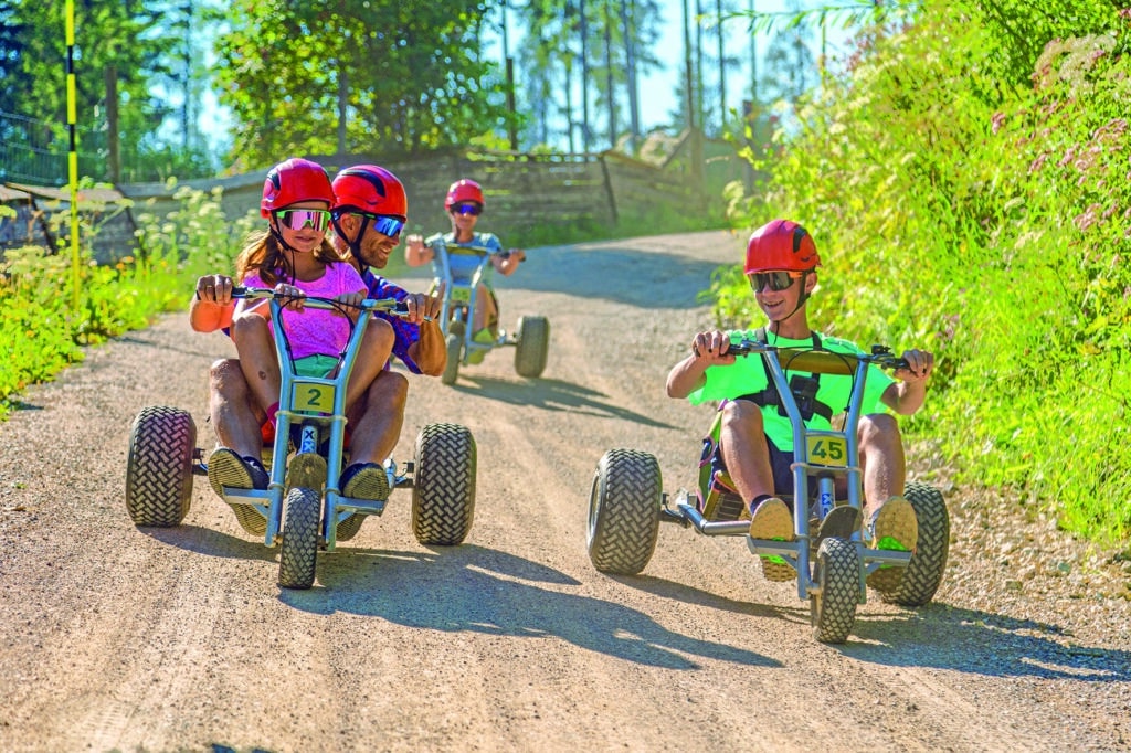Familien fahren mit Mountainkarts über eine Schotterstrecke am Wilden Berg Mautern.