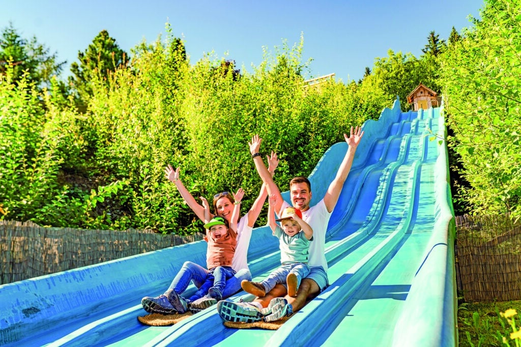 Familie rutscht gemeinsam auf der Riesenrutsche im Spielpark am Wilden Berg Mautern.