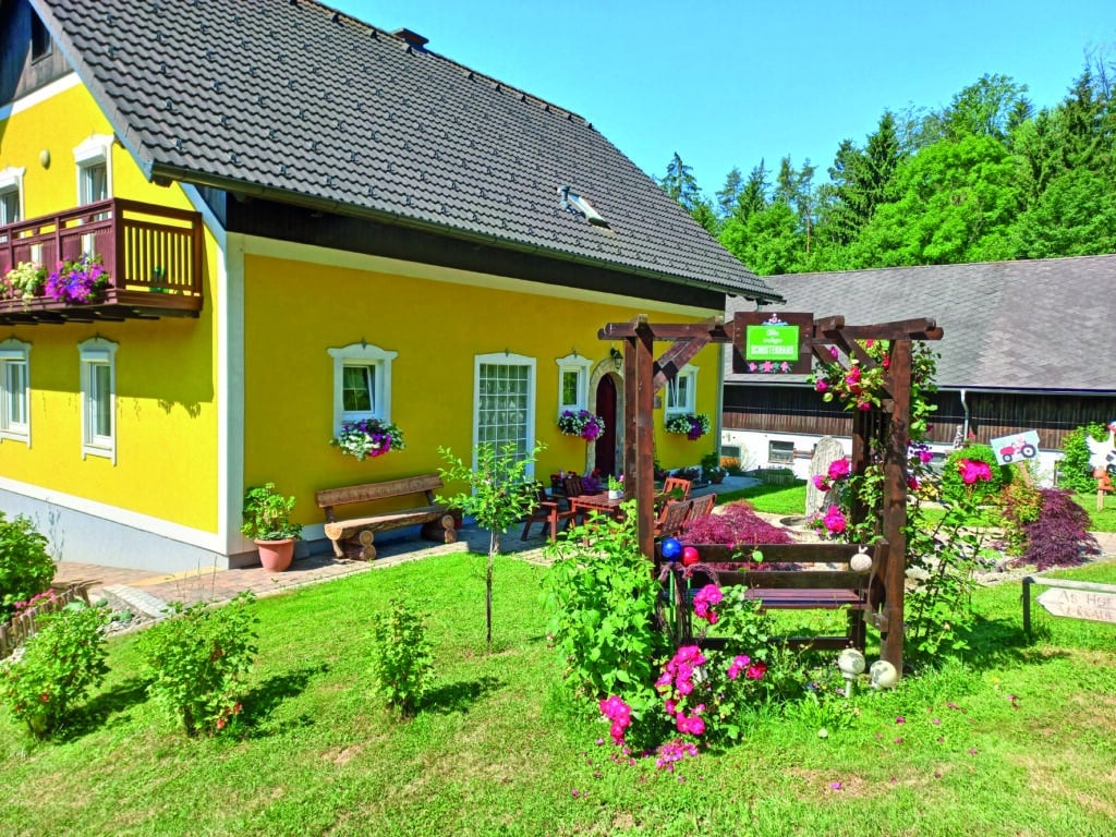 Außenansicht des Schusterhans-Hofs in Semriach mit Garten und Sitzbereich.