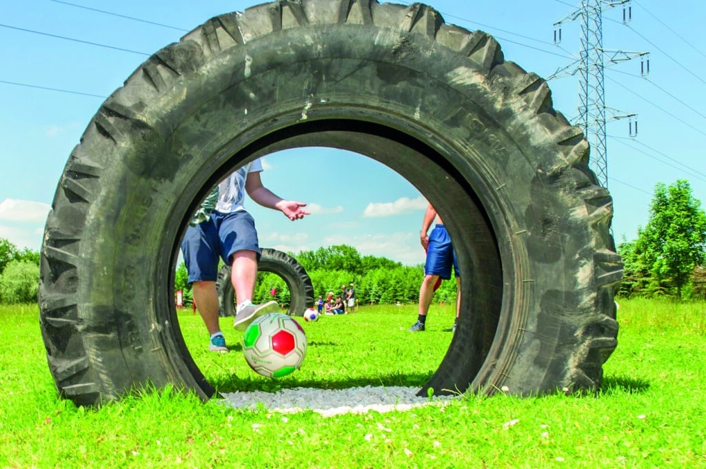 Spieler schießt einen Fußball durch ein großes Reifenhindernis im Soccerpark Salzburg.