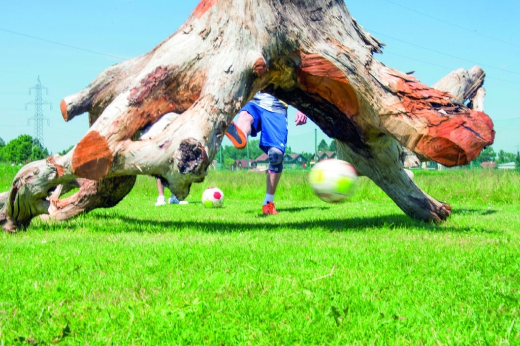 Spieler schießt einen Fußball unter einem Wurzelhindernis im Soccerpark Salzburg.