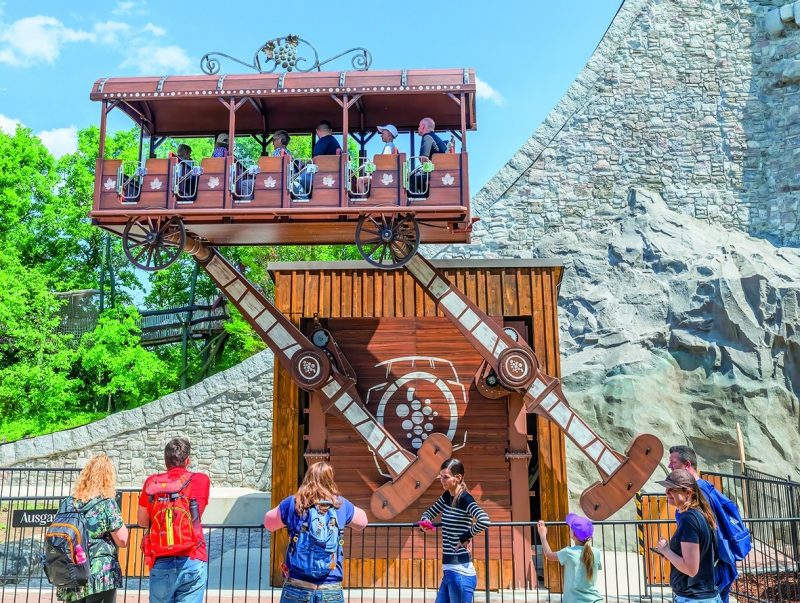 Familien fahren mit der Attraktion „Wilder Winzer“ im Familypark in einem hölzernen Wagen auf und ab.