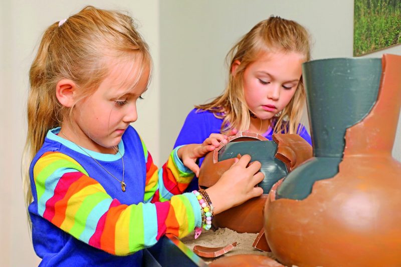 Zwei Kinder entdecken eine interaktive Keramikstation zur Hallstattzeit im Jungen Museum des KulturQuartiers Leoben.