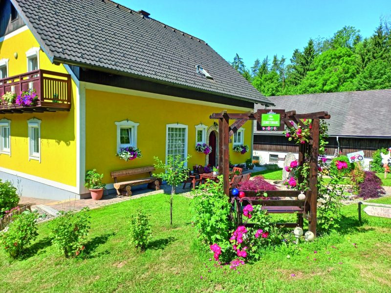 Außenansicht des Schusterhans-Hofs in Semriach mit Garten und Sitzbereich.